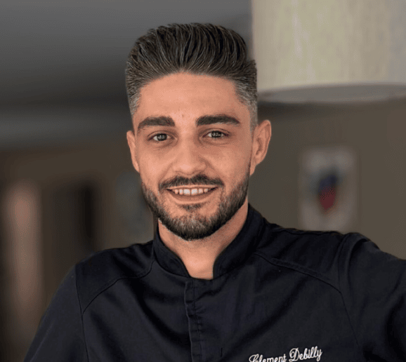 Portrait d'un chef cuisinier souriant en veste noire dans un environnement de cuisine professionnelle