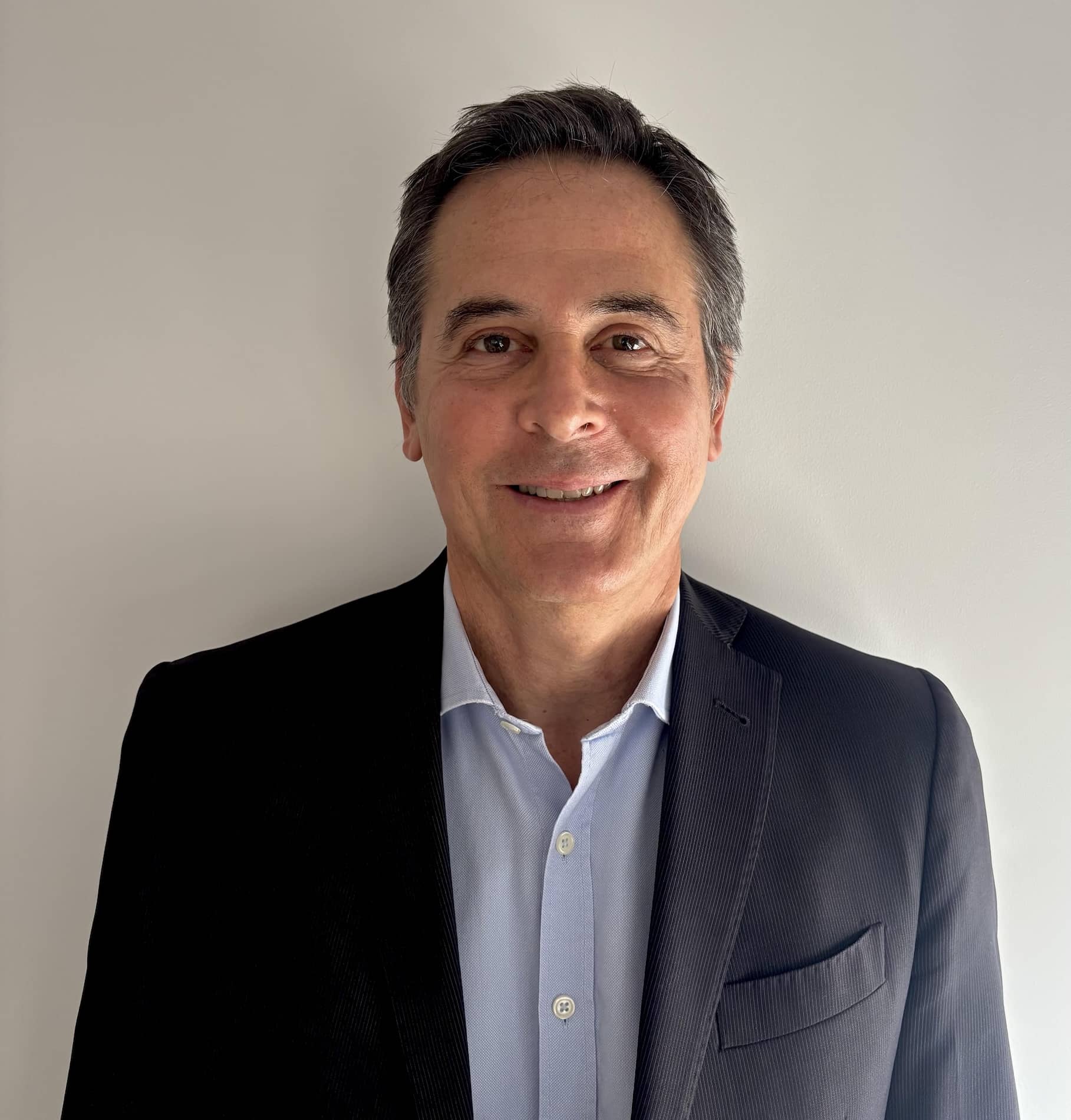 Portrait professionnel d'un membre de l'équipe en costume bleu foncé sur fond neutre