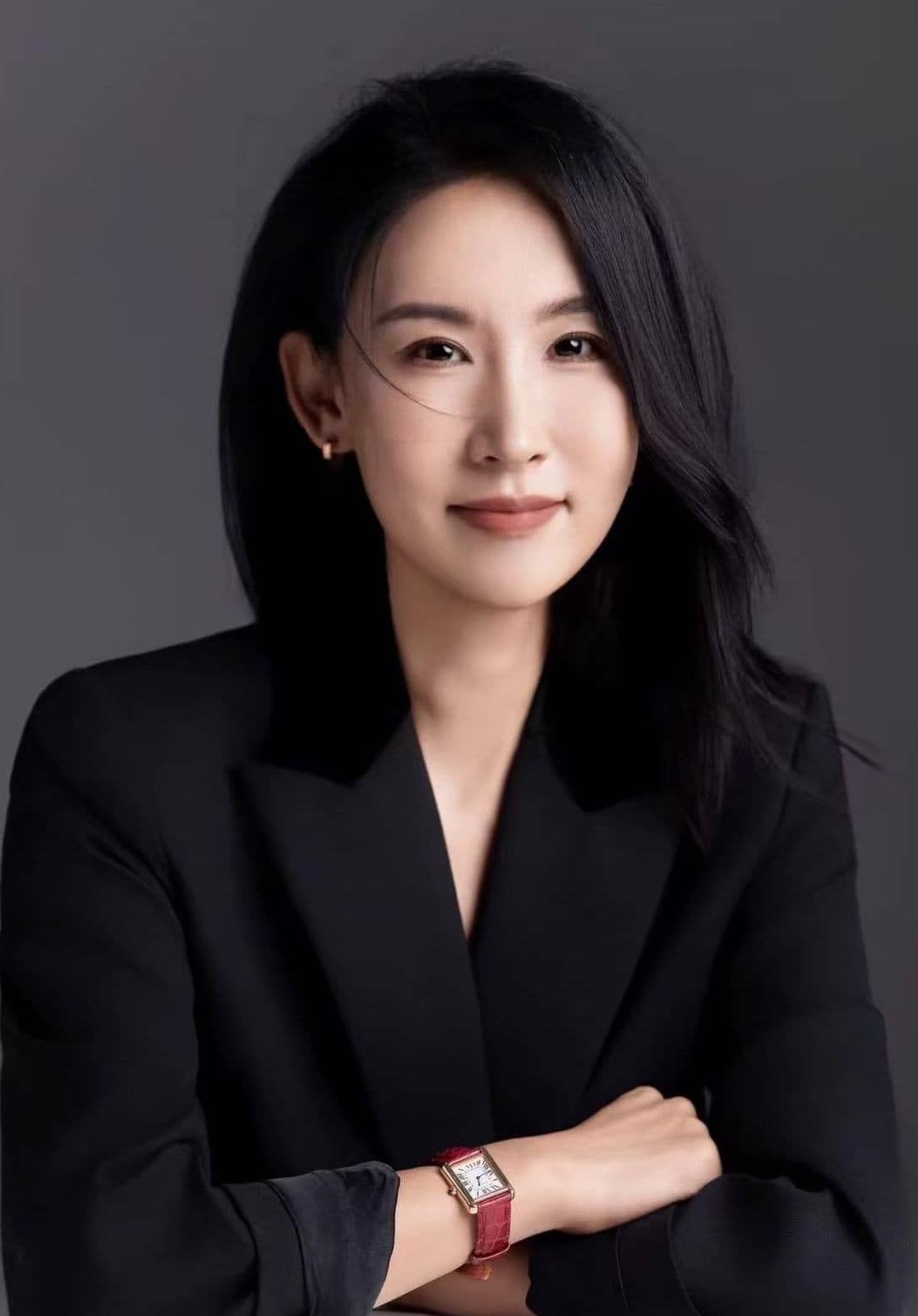 Portrait professionnel d'une membre de l'équipe en costume noir avec lunettes et cheveux longs sur fond gris